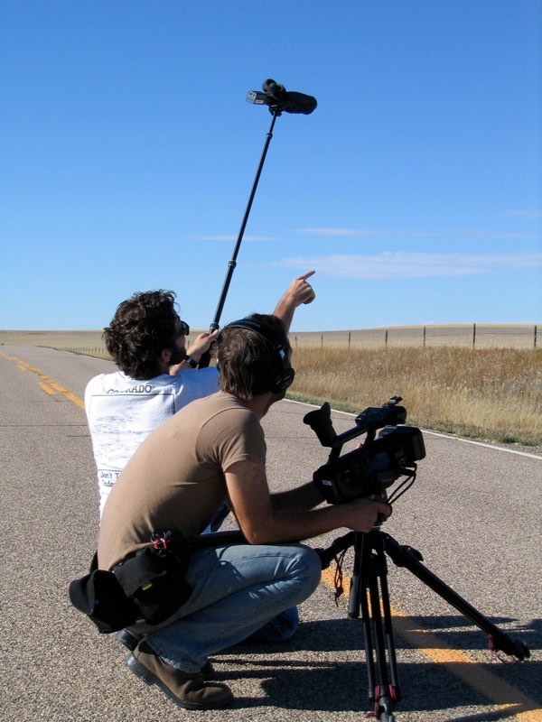 The crew films Gordon on an empty highway under a big sky.