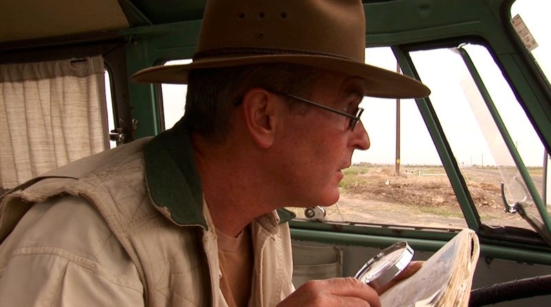 Gordon in a wide-brimmed hat reads in his van.